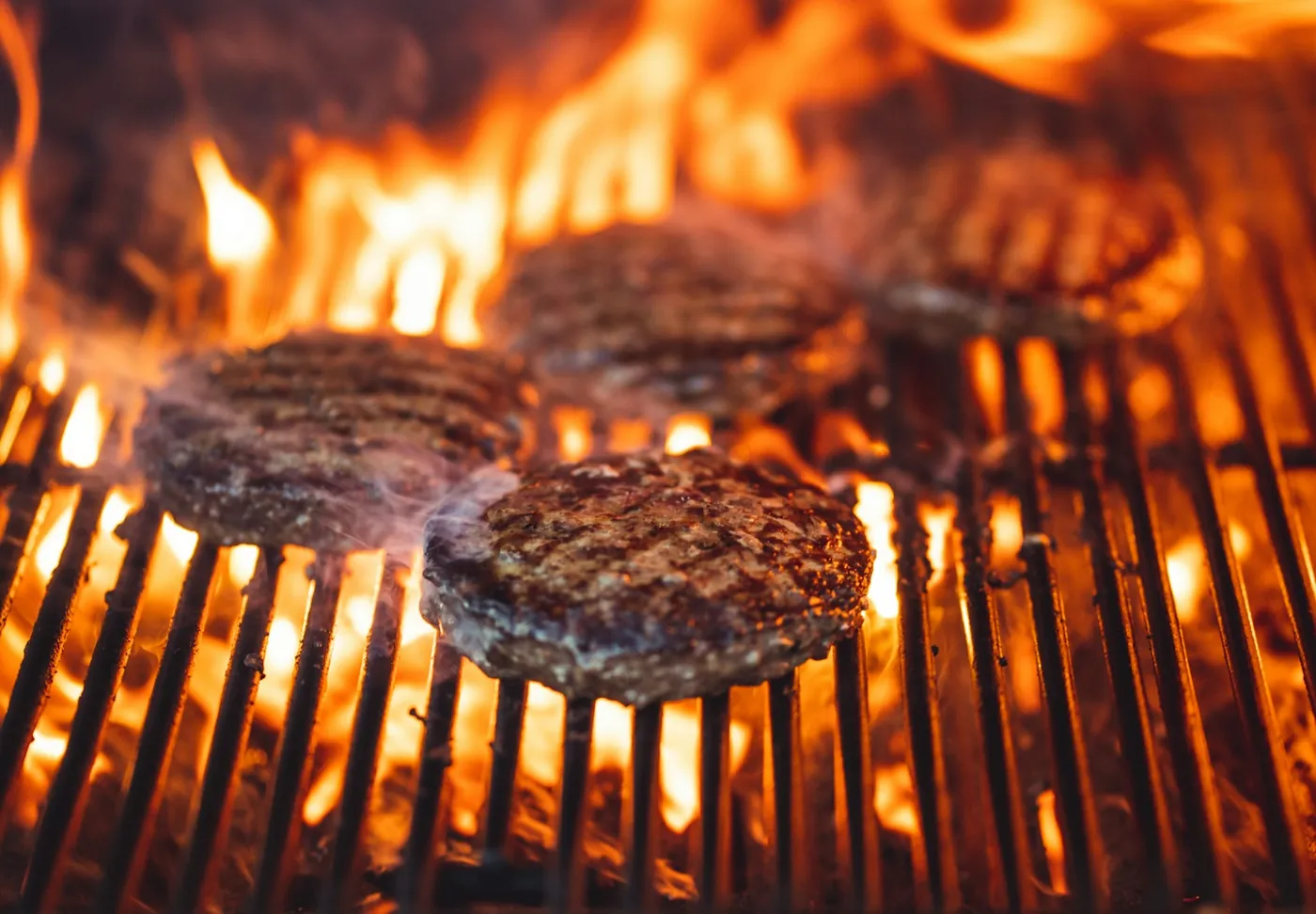 Burgerkød tilberedes over åben ild på grillen